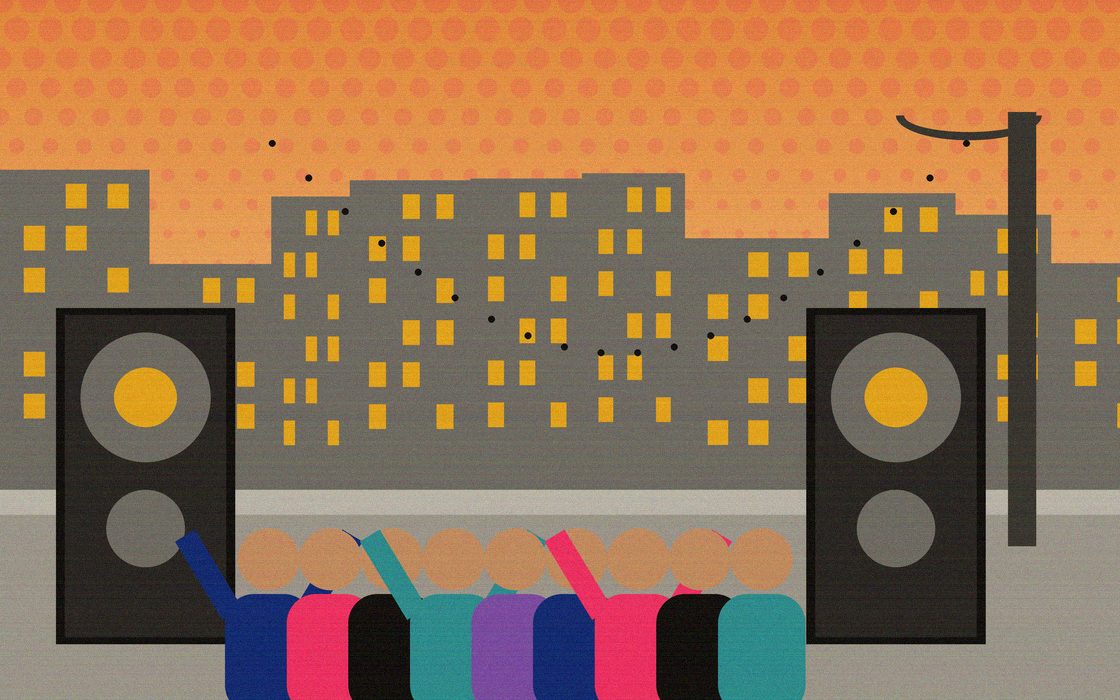 An outdoor block jam with speakers stacked by a lamppost and a crowd dancing