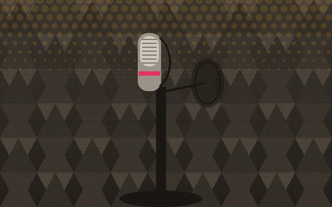 A recording booth with a microphone, pop filter and headphones under warm light